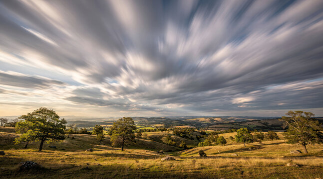 Dramatic long exposure clouds over a scenic rolling hill landscape at sunset