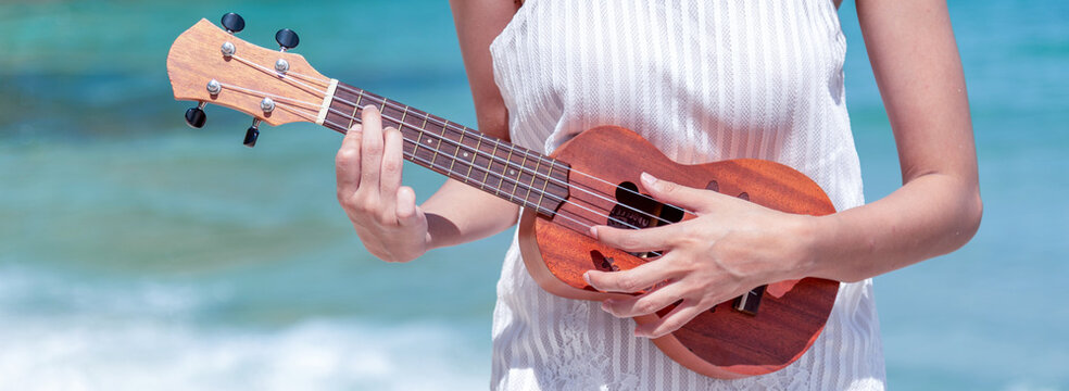 Happy musician guitarist girl. Happy Woman person playing acoustic guitar music Ukulele soprano seaside sand tropical beach island. Ukulele playing on beach Young woman acoustic guitar summer beach