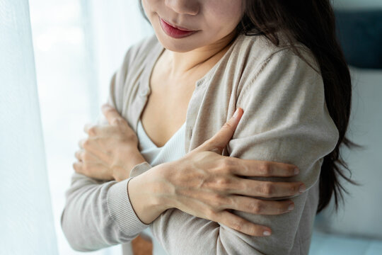Cropped shot of a gentle woman hugging herself with a subtle smile and feeling safe, peaceful indoor lifestyle concept.