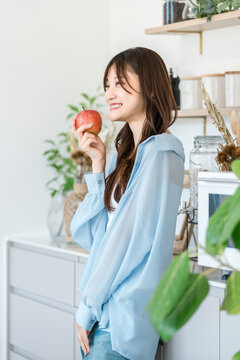 A woman eating an apple in the kitchen (diet, vegetarian)