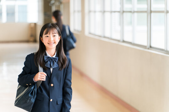 Elementary, middle, and high school girls in uniform walking down a school corridor.