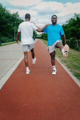 Obraz premium Two black men stretching on running track