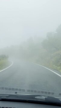 Car dashboard camera view driving on winding foggy mountain roads moving toward the scenic peak.