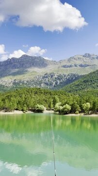 Peaceful high-altitude woodland lake featuring stunning natural reflections of distant majestic mountains and dramatic skies