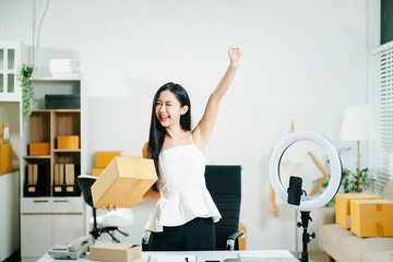 Asian woman livestreaming and packing orders in a home office. ecommerce, online shopping, content...