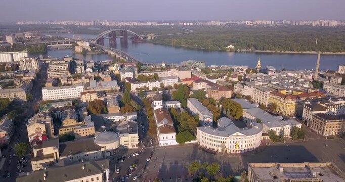 Drone footage of Kyiv's historic Podil district overlooking the Dnipro River. Panoramic city view featuring architecture, waterfront and the skyline of Ukraine's capita