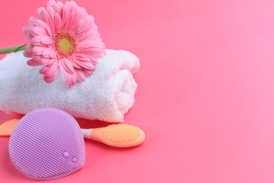 Cleaning tools and flower on a pink background for personal care and skincare routines