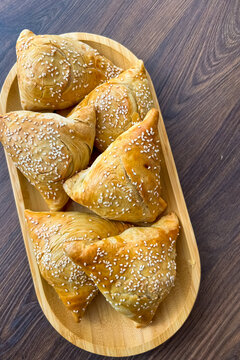 Freshly baked pastries sit on a wooden platter as they cool in a kitchen