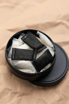 Snus pouches placed inside a black container on a brown background for better organization and storage