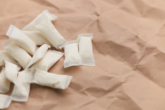 Nicotine pouches are placed on brown paper in a relaxed setting during daytime hours