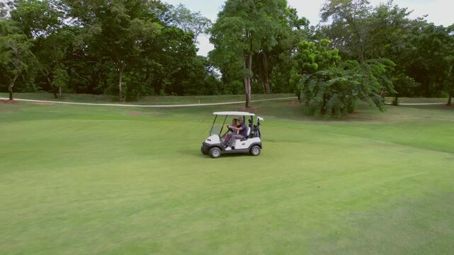 Drone view of golfers people riding together in golf cart on course. 