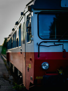 Close-up of a passenger railcar at a station in northern Sweden during golden hour. Side perspective highlights the train's classic design with warm evening light and shallow depth of field.
