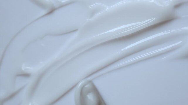 Creamy cosmetic product smearing on white surface for rich texture and skincare concept