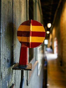 Vintage railway semaphore signal mounted on the wall inside a historic railway building. Close-up of a traditional mechanical train signaling device with a softly blurred station corridor in the backg