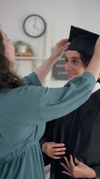 Latino mother hugging young daughter while celebrating college graduation. 
