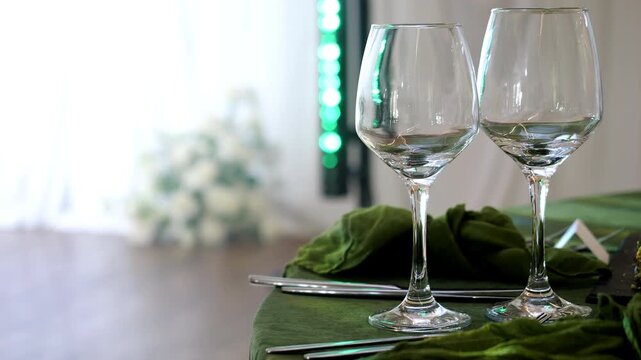 Elegant empty stemware on a beautifully decorated reception table with soft wedding decor in the background. Refined table setting prepared for guests at a celebration or special event.