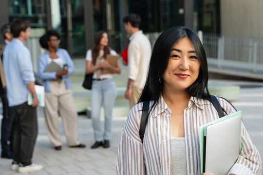 Portrait confident young Asian student standing at university campus looking to camera with happy expression
