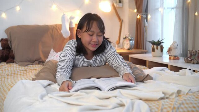 Smiling  focused young girl doing reading on Bed with Laptop in Cozy Bedroom at home	
