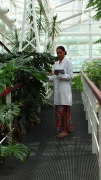 Female botanist studying tropical plants in a greenhouse