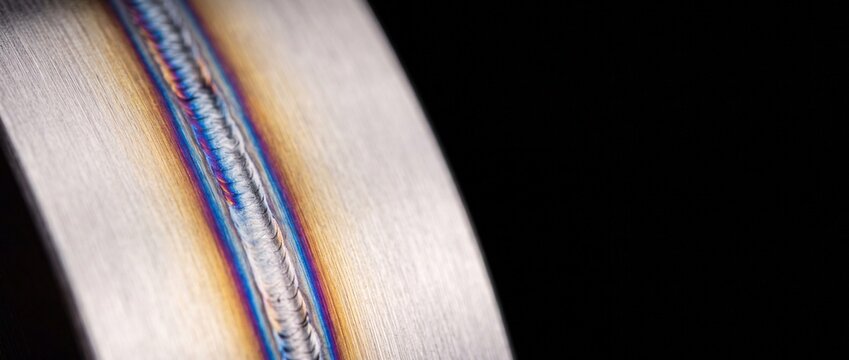 Professional tig welding bead on stainless steel pipe showing colorful heat tint and perfect craftsmanship for industrial systems.