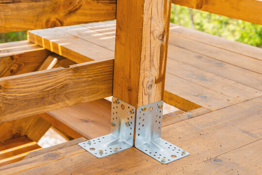 Metal post base bracket securing wooden post to deck during outdoor construction project.