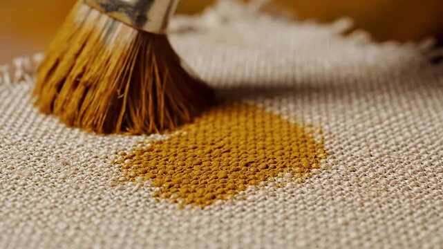 Close-Up Shot Of A Natural Pigment Being Brushed Onto Textured Fabric Canvas For Artistic Painting Applications In Warm Background