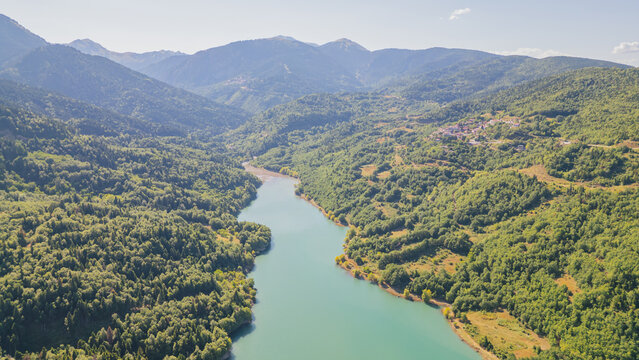 High angle aerial view of calm turquoise river flowing through lush green mountain valley towards Lake Plastiras in Karditsa Thessaly Greece for travel background