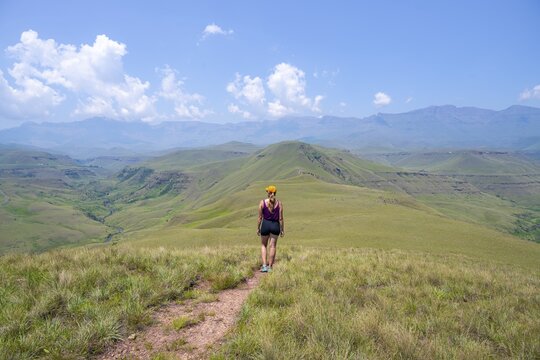 Green hills and valleys, young woman hiking through landscape, Worlds View Hike, Drakensberg, South Africa