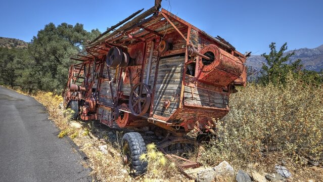 Abandoned, rusty machine next to a road with lush vegetation and mountain views in the background, Amari Basin, Amari, Central Crete, Greek Islands, Greece