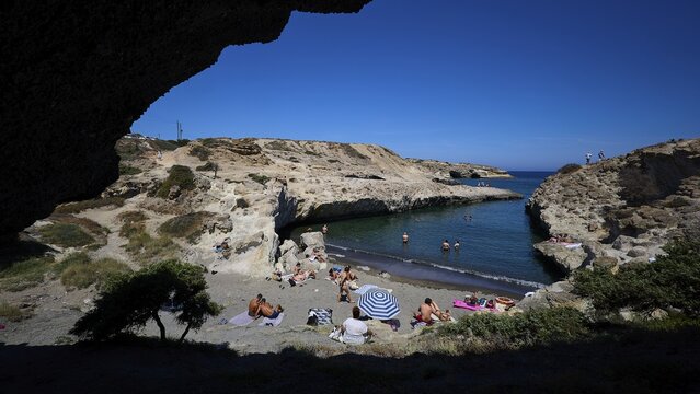 People relaxing on the beach in a rocky bay in the shade with a view of the open sea, Kapras, Kapros, Beach, Kapros Beach, Caves, Paralia Kapros, Milos, Cyclades, Greek Islands, Greece