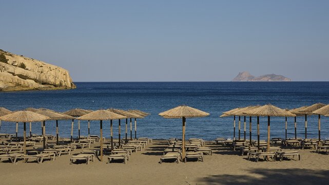Paximadia island, quiet beach with umbrellas and deckchairs, view of a distant island, Matala, south coast, Crete, Greek Islands, Greece