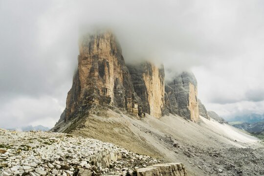 Dramatic misty Tre Cime di Lavaredo area. Dynamic clouds after rain move over the rugged limestone peaks of the Italian Dolomites. Three sisters circular loop popular trail summer