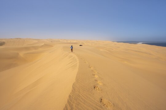 Lonely people between sand dunes with wave patterns, dune sea, sandy desert, impressive desert landscape, Namib Naukluft Park, Namib Desert, Namibia