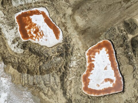 Saline ponds with ruddy algae growth and white salt deposits at the Skeleton Coast. Aerial view. Drone shot. Namib Desert, Dorob National Park, Namibia