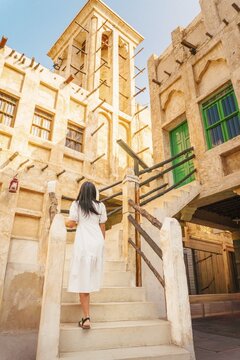 Doha Qatar Katara Cultural Village woman climbing stairs traditional wind tower architecture mud brick heritage site sunny day travel tourism Middle East Qatari culture exploration