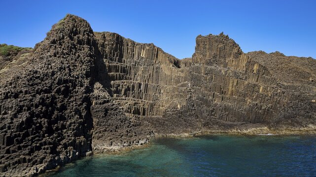 Wide rock wall with geological patterns merging into the sea, Glaronisia, Glaronesia, Milos, islets, hexagonal basalt columns, north of Milos, destination by boat, Cyclades, Greek Islands, Greece