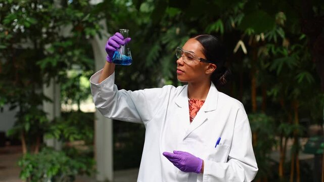 Female scientist examining a blue chemical liquid in a glass flask