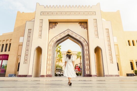 Doha Qatar Katara Cultural Village woman walking toward grand ornate archway gate traditional Islamic architecture heritage site sunny day travel tourism Middle East Qatari culture