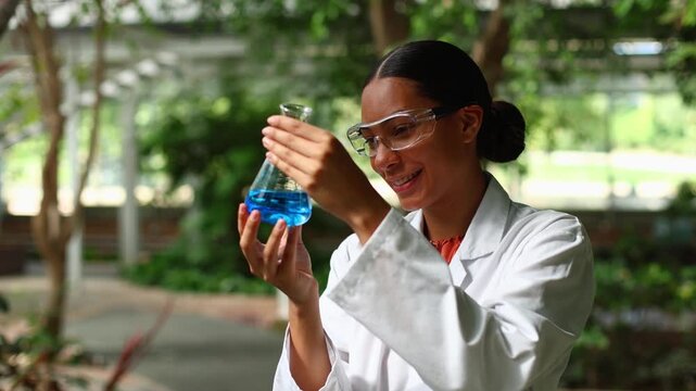 Female scientist analyzing blue liquid in a flask