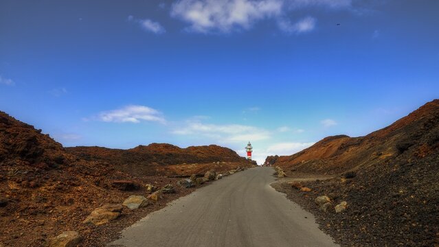 Punta de Teno, Lonely road leads to a lighthouse through red rocks under blue sky, Masca, Barranco de Masca, canyon, Teno, Teno Mountains, northwestern Tenerife, Tenerife, Canary Islands, Spain