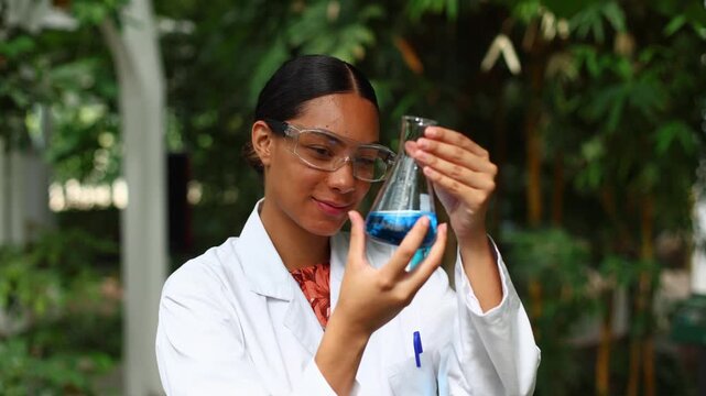 Female scientist examining blue liquid in a flask