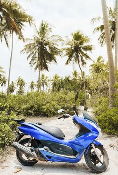 Bright blue typical common motor scooter parked on sandy dirt road. Transportation rentals in asia. Safety and and road trip concept. Travel like a local