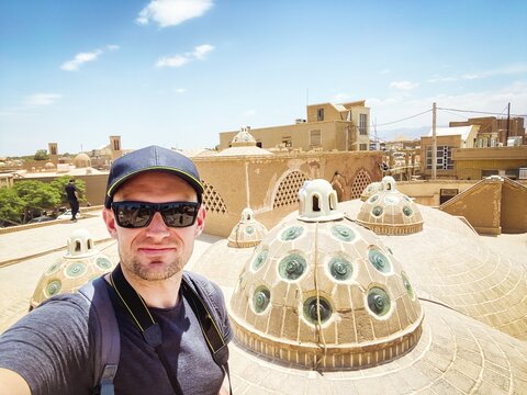 Young caucasian male tourist take selfie on famous bathhouse rooftop in poplar travel destination, sultan amir ahmad in KAshan city landmark. Iran