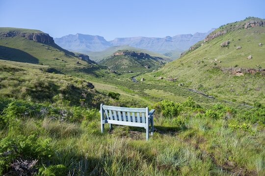 Blue park bench in a green idyllic mountain valley with river, Giant's Castle, Maloti-Drakensberg Park, Drakensberg Mountains, South Africa