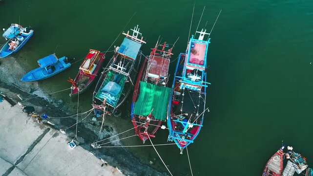 Fishing Boats Docked at Harbor: An aerial view showcases a fleet of colorful fishing boats moored at a tranquil harbor, their nets neatly stowed, ready for the next voyage.