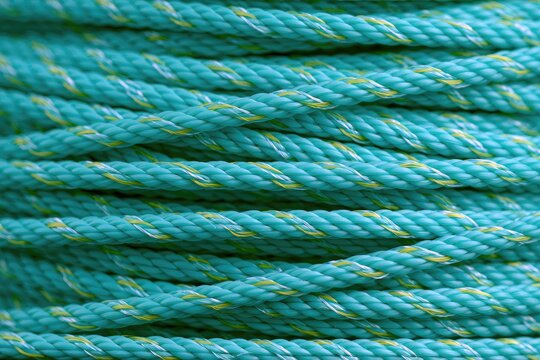 Tightly wound, turquoise and yellow twisted synthetic fibers forming a textured pattern