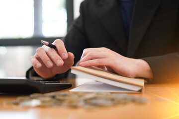 Fototapeta premium Close-up of a business professional reviewing financial notes while using a calculator with coins, representing budgeting, financial planning, accounting, savings, and investment management.