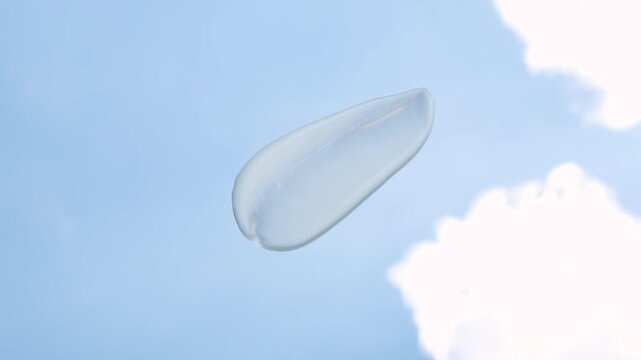 Smear of moisturizing cream against background of sky and clouds.