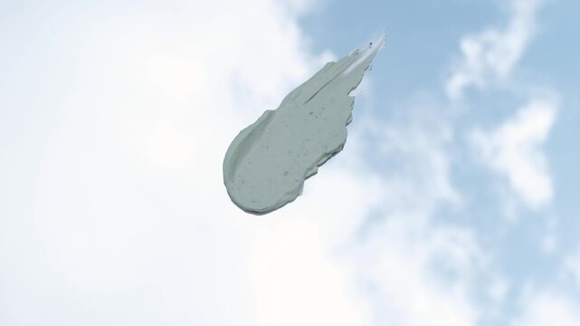 Green cosmetic clay smear against the background of sky with clouds close-up.