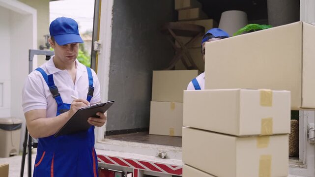 Home moving and delivery service concept. Teamwork of professional home and furniture moving with a truck from business service company. Two male movers in uniforms working and delivering to customer.